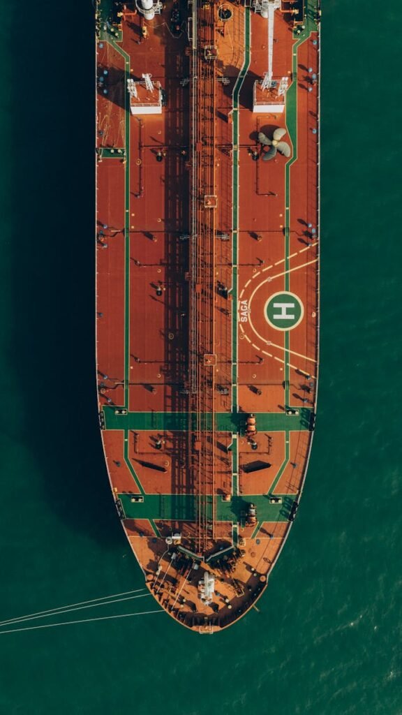 A stunning aerial view captures a large cargo ship navigating through the turquoise sea waters near Georgia.